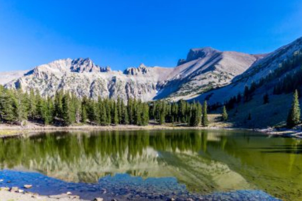 A glassy alpine view of Stella Lake with large glacial erratic boulders