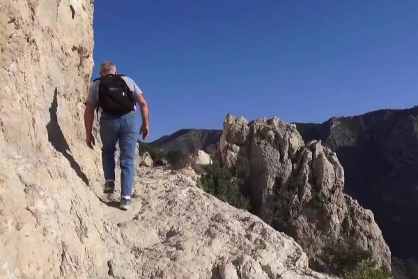 A hiker at the metal pyramid summit marker on Guadalupe Peak