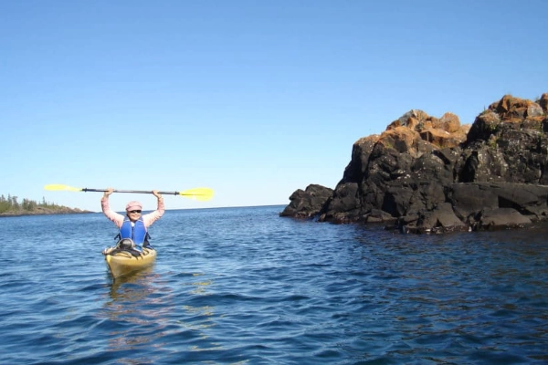 A kayaker paddling along the rugged shoreline in a secluded cove