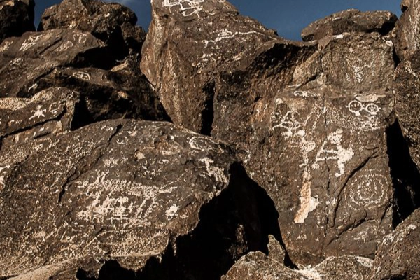 Ancient Apache carvings of bighorn sheep and spirits on a dark rock
